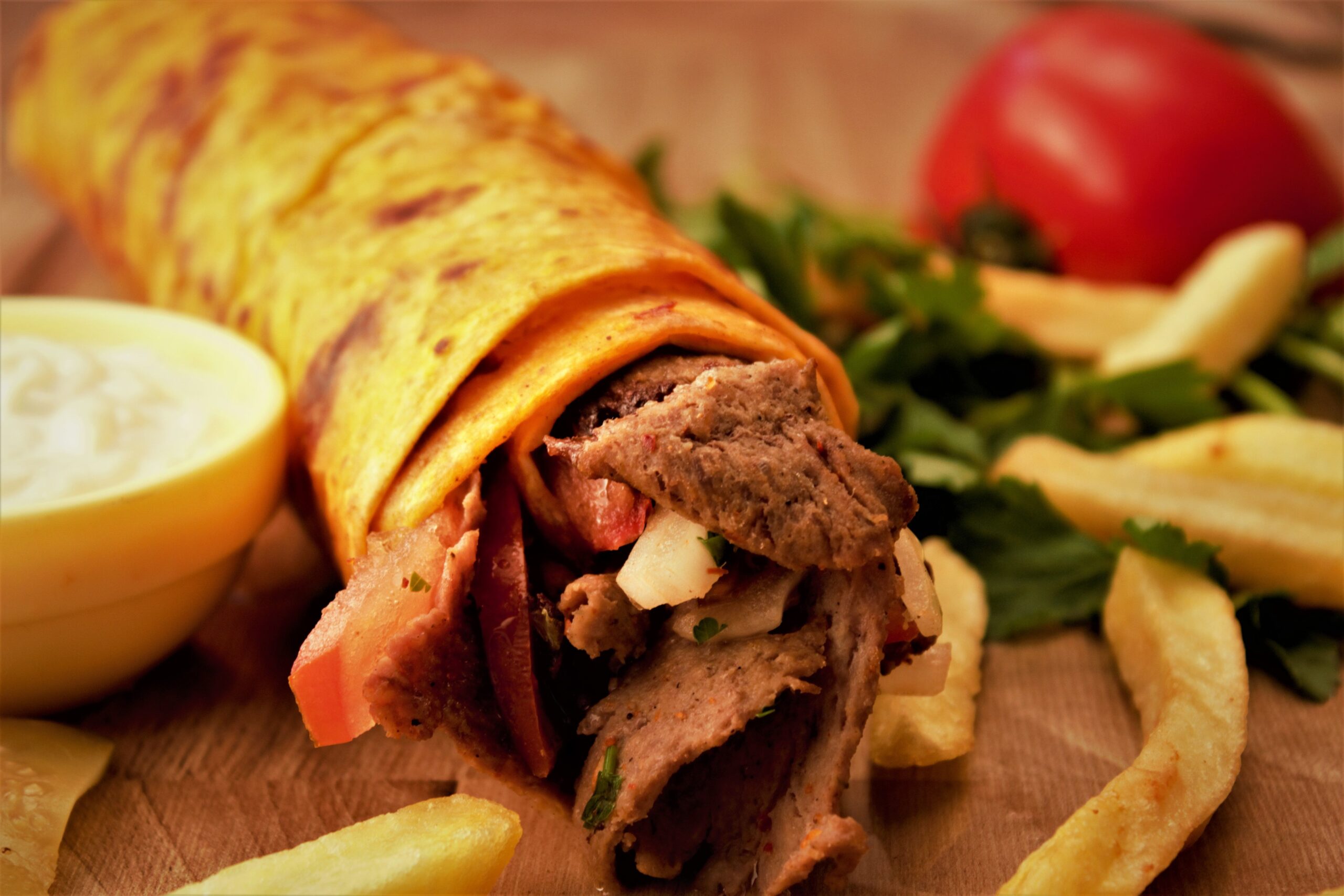 Close-up of a flavorful Turkish kebab wrap with fresh fries and vegetables.